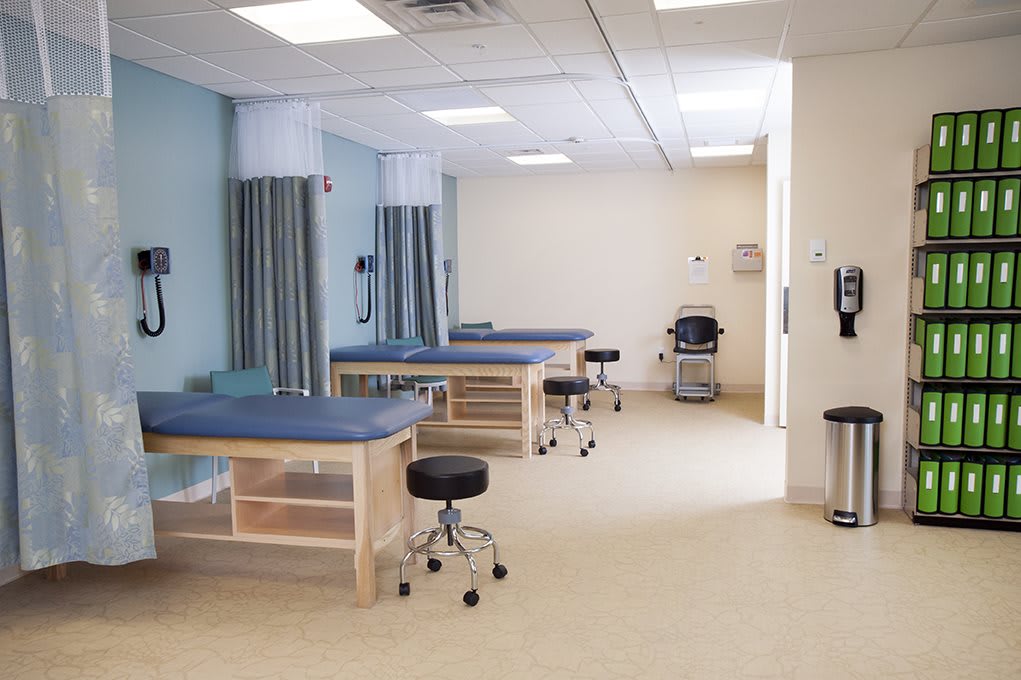 A clean and organized medical treatment area with examination beds and curtains for privacy.