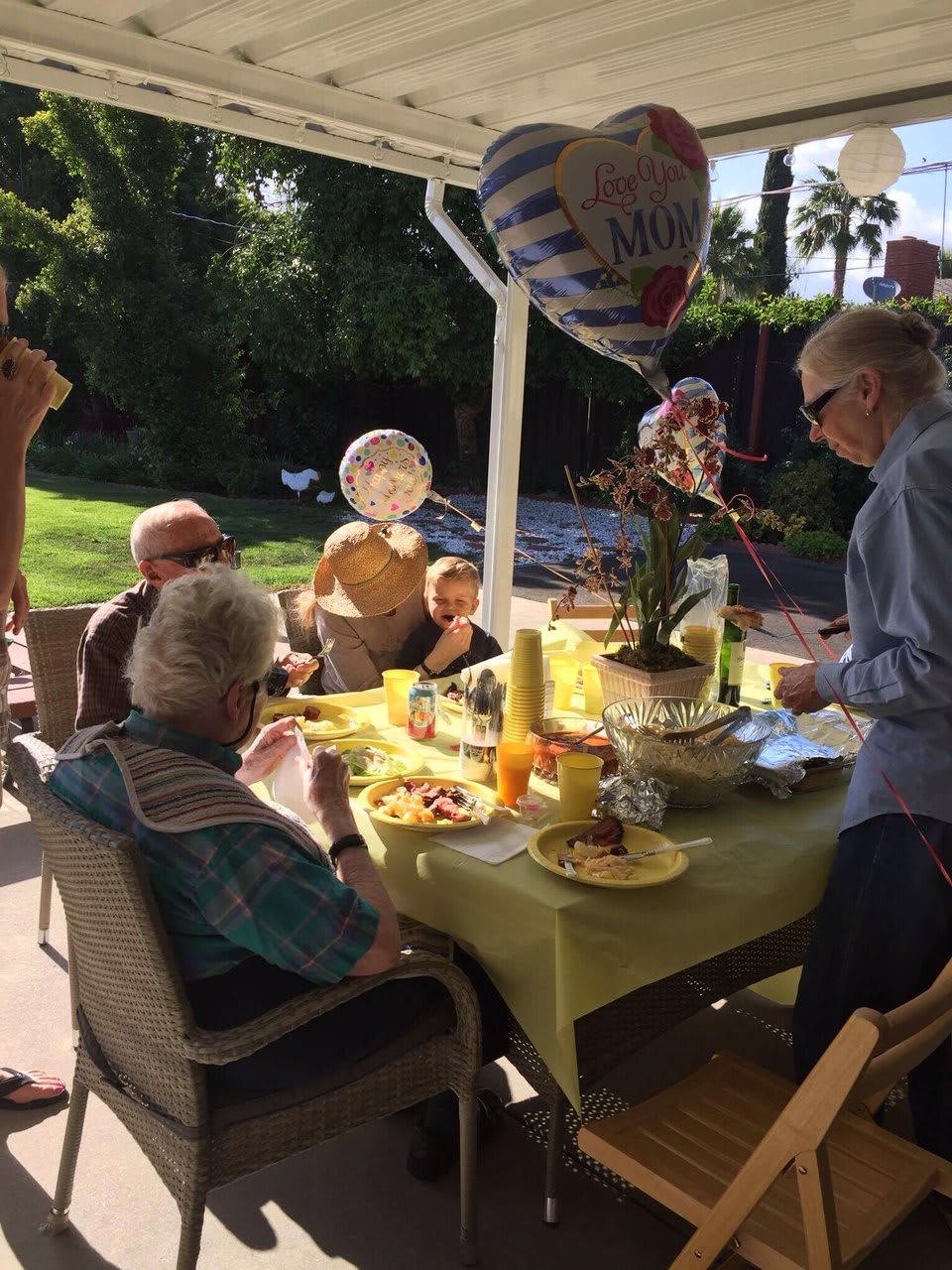 A family gathering outside for a meal, with decorations and balloons.
