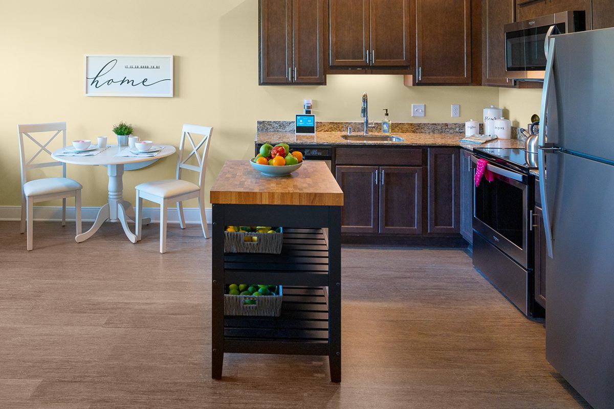 A cozy kitchen with a central island, featuring wooden cabinets and a small dining area.