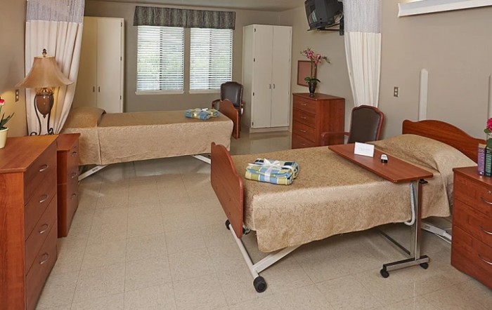 A hospital room with two beds and basic medical furniture.