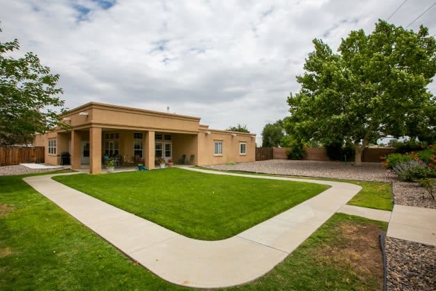 A modern single-story house with a well-maintained lawn and clear pathways under a cloudy sky.