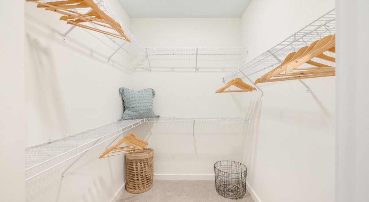 A spacious, empty walk-in closet with wire shelving and wooden hangers.