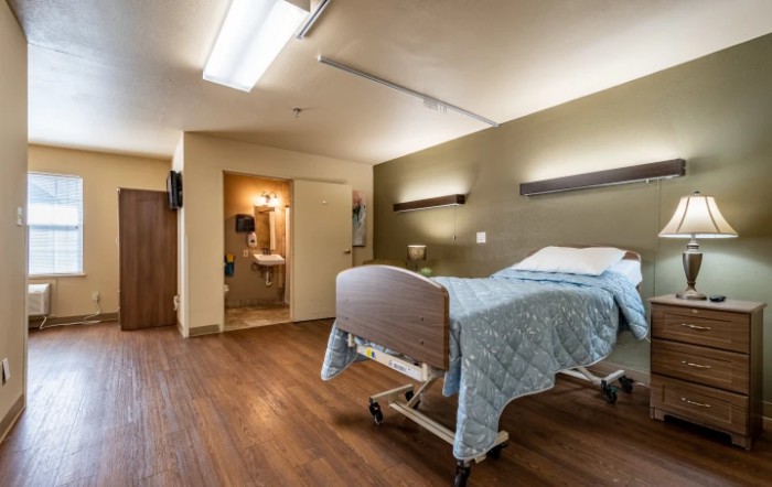 A clean and organized hospital room with a single bed and attached bathroom.