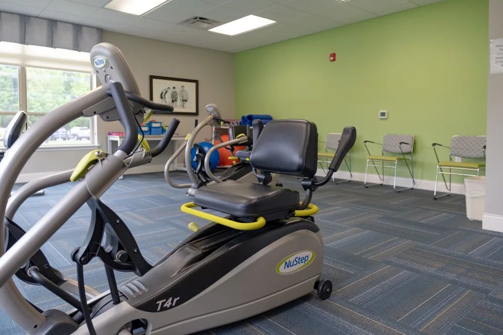 A well-lit gym featuring an exercise bike and other fitness equipment.
