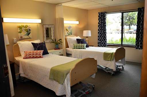A comfortable and well-lit hospital room featuring two patient beds with decorative pillows.