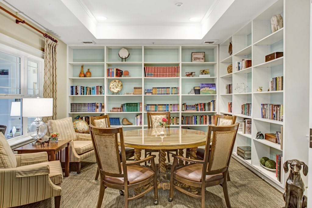 A cozy library with bookshelves, a round table, and chairs for reading and discussion.