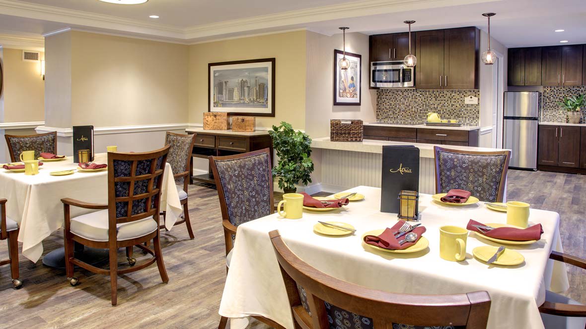 A modern dining area with a well-set table, featuring contemporary decor and kitchen space.