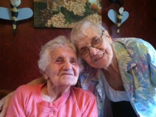 Two elderly women smiling together, showing friendship and warmth.
