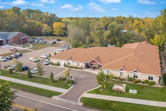 Aerial view of a suburban building with a parking lot surrounded by trees.