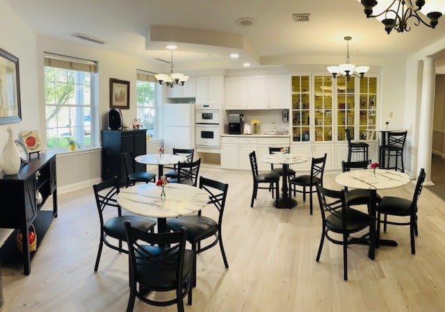 A modern kitchen and dining area with round tables and black chairs.