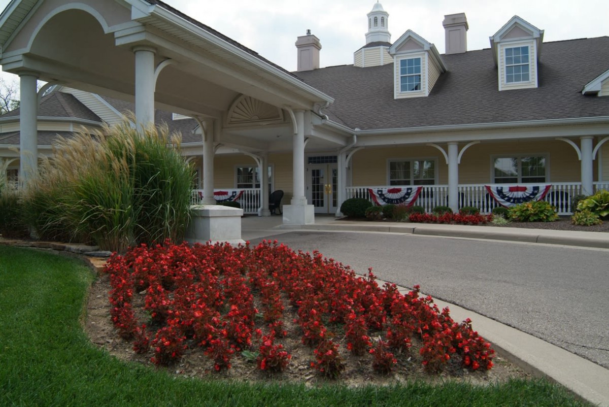 A beautifully landscaped entrance with vibrant red flowers in front of a large building.