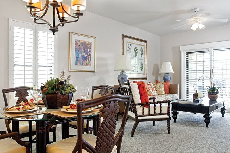 A cozy living and dining area with elegant furniture, decorative artwork, and warm lighting.