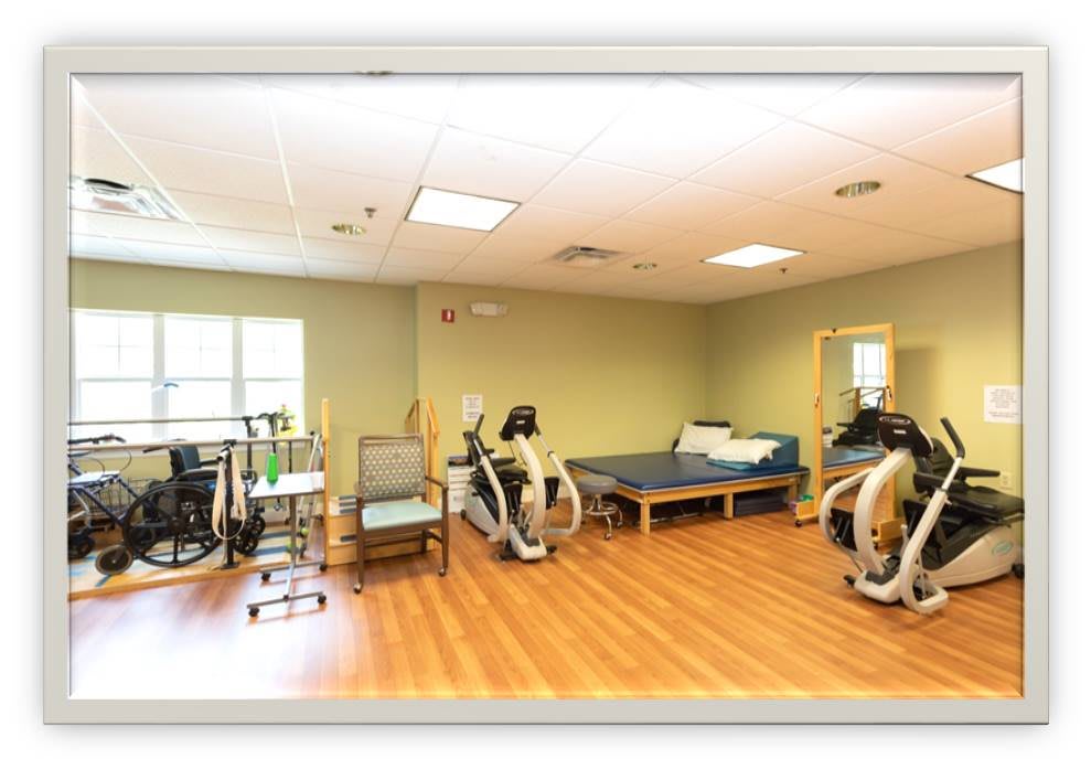 A spacious physical therapy room equipped with exercise machines and therapy beds.