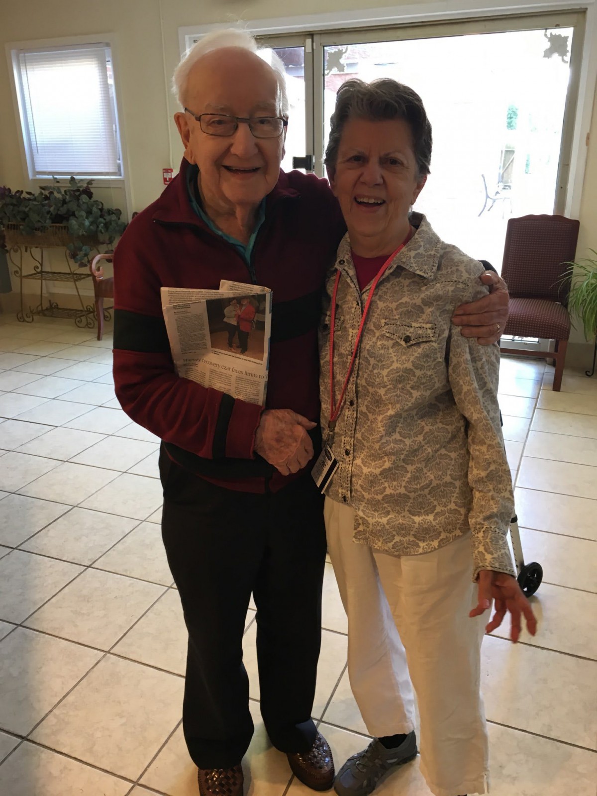 An elderly couple smiling and hugging indoors.