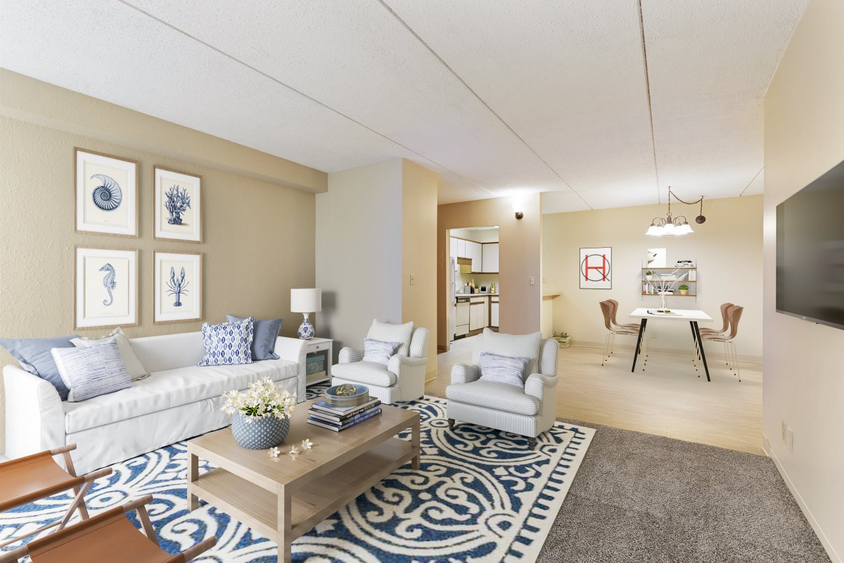 A cozy and elegantly decorated living room featuring a sofa, armchairs, a coffee table, and artwork on the walls.