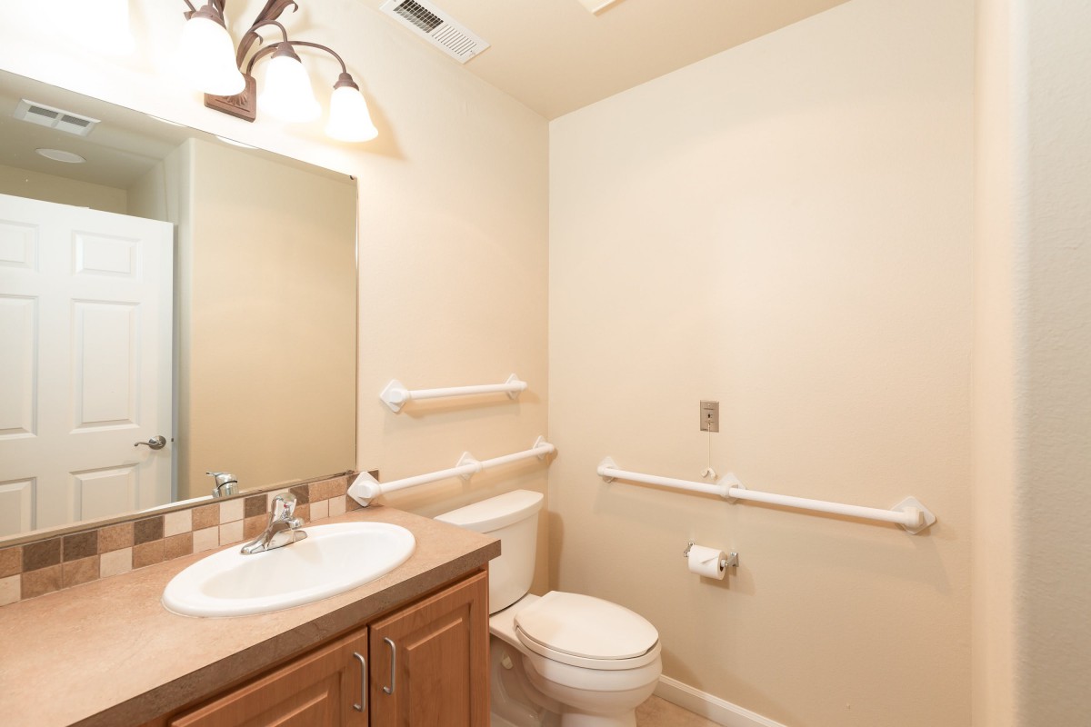 A well-lit bathroom with a sink, mirror, and toilet.