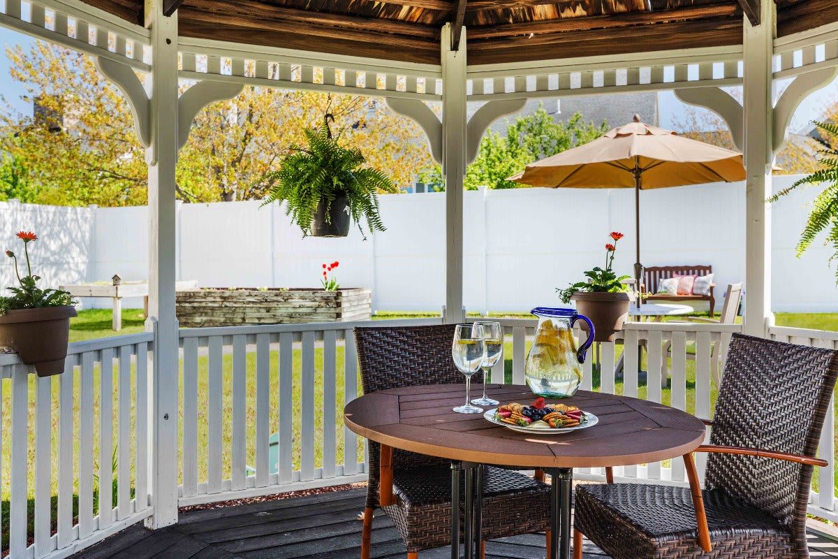 A cozy gazebo featuring a table set for dining with plants and a garden view.