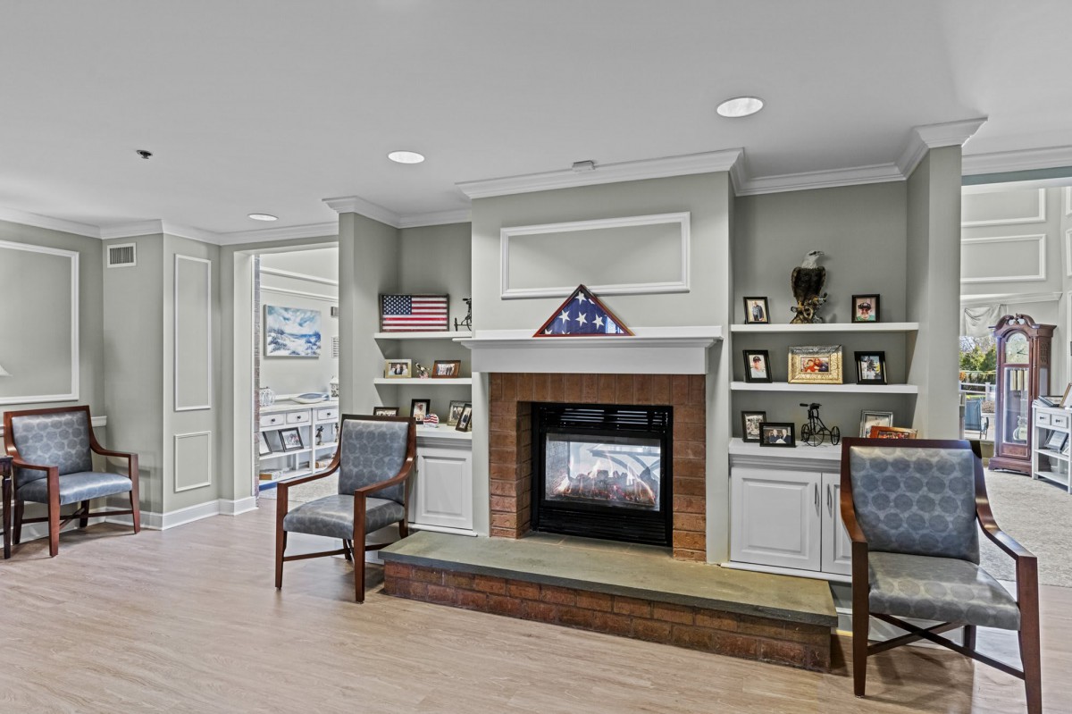 A cozy living room featuring a central fireplace with built-in shelves adorned with various decorations and two chairs on either side.