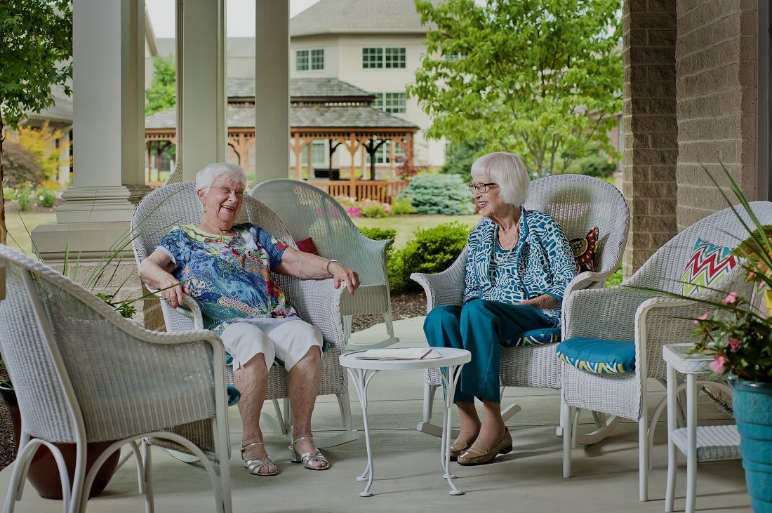 Two elderly women enjoying a conversation on a patio.
