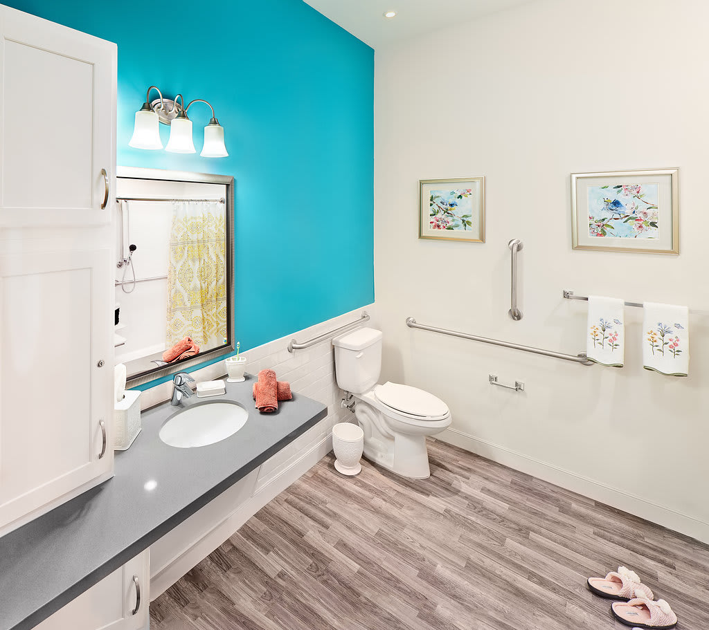 A modern bathroom interior with bright blue and white walls, featuring a sink, mirror, toilet, and stylish flooring.