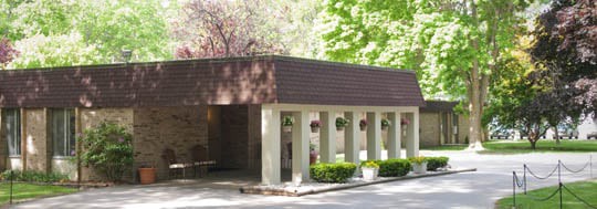 A small, modern building surrounded by trees and natural light.