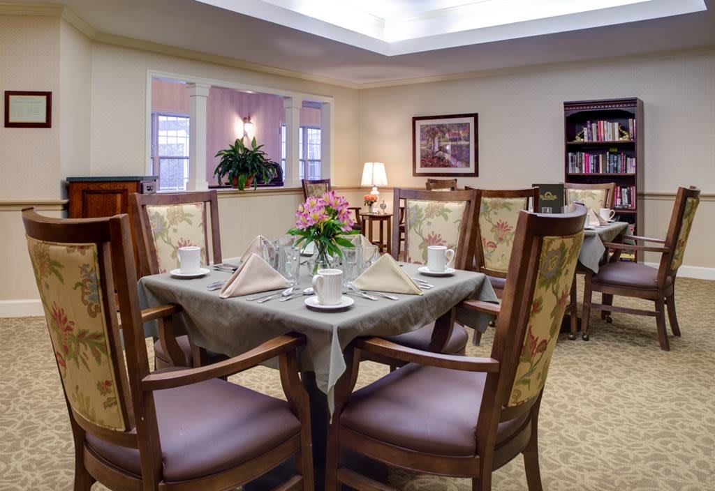 A cozy and elegantly decorated dining room with a neatly set table and comfortable chairs.
