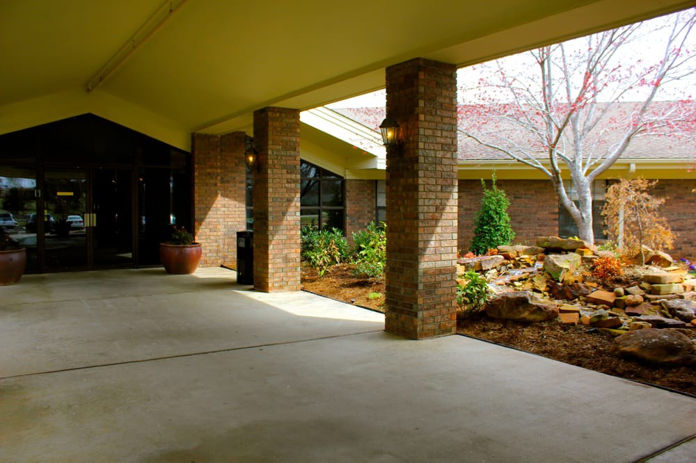 The entrance of a building featuring brick columns and landscaped surroundings.