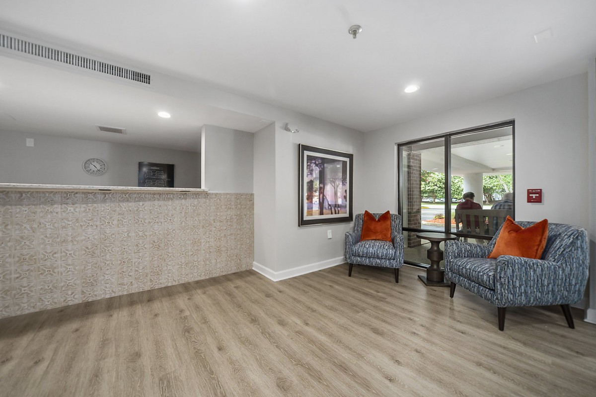 A modern living room with wood flooring and a comfortable seating area adorned with colorful cushions and artwork.