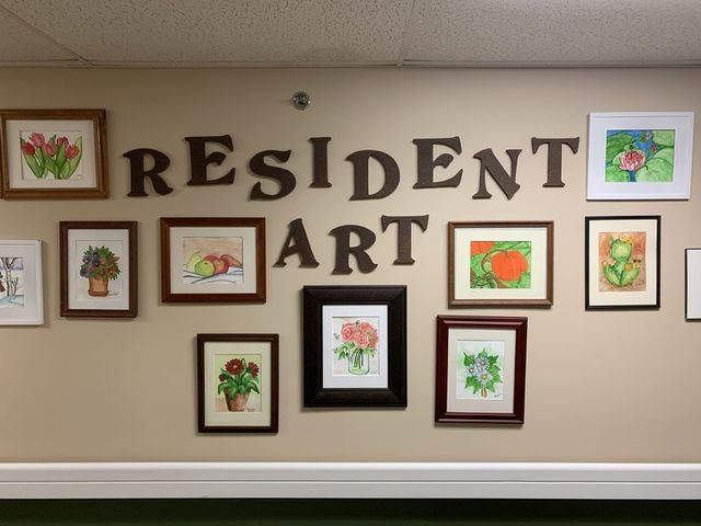 A wall displaying 'Resident Art' with several framed paintings.