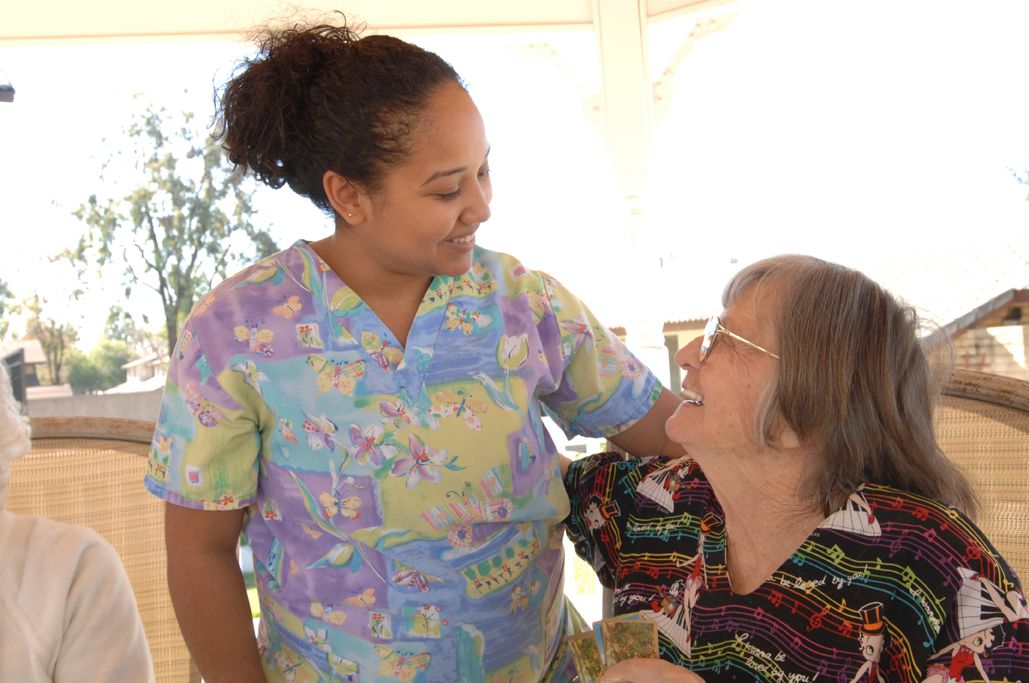 A caregiver shares a warm moment with an elderly person.