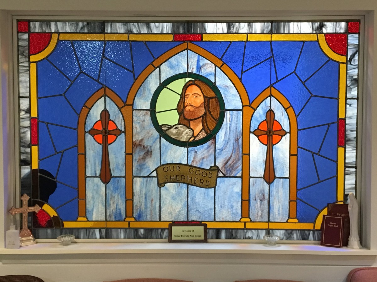 A stained glass window featuring a depiction of Jesus in a church setting.