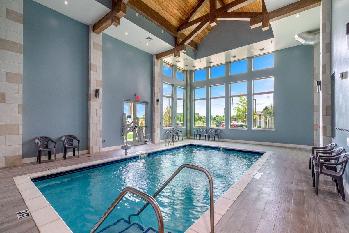 A bright indoor swimming pool with large windows and a vaulted ceiling.