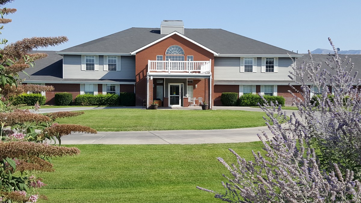 A large residential house with a well-maintained lawn and clear blue sky.