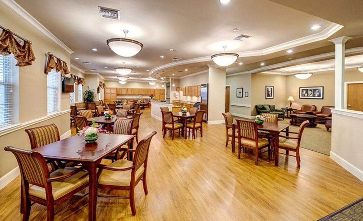 A spacious dining area with wooden tables and chairs, featuring elegant lighting and hardwood floors.
