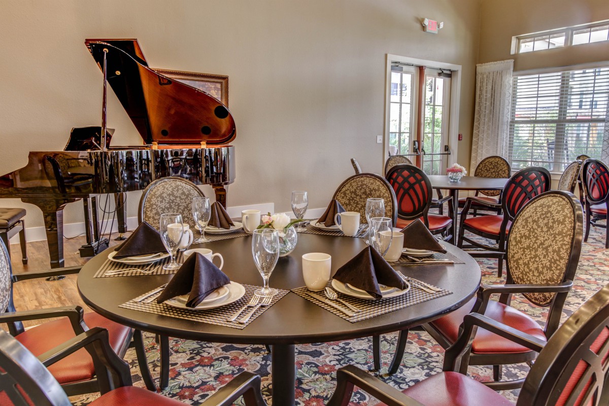 A beautifully set dining table in an elegant room with a grand piano in the background.