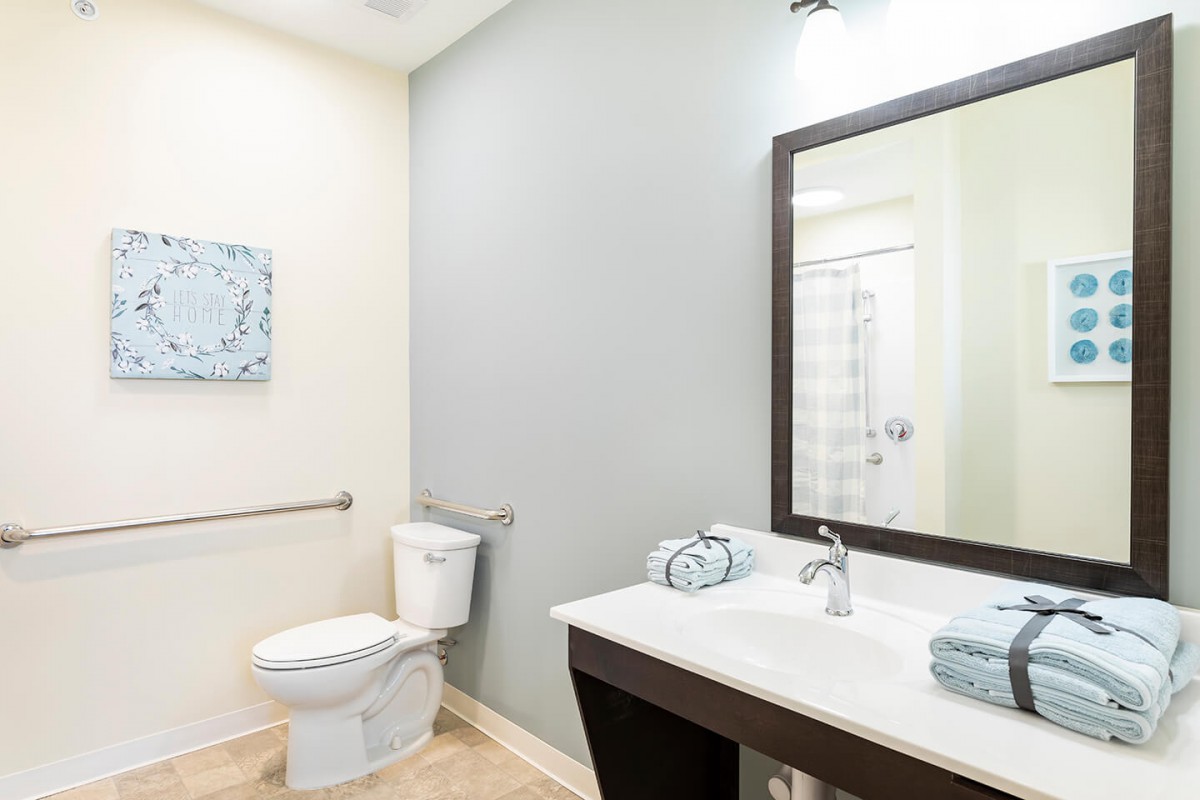 A modern bathroom featuring a sink with a large mirror and a toilet.