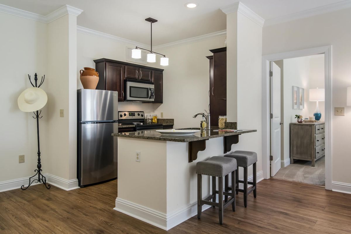 A modern kitchen featuring stainless steel appliances, a central island with bar stools, and elegant lighting.