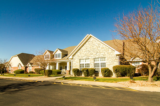 A suburban residential house with a stone facade under a clear blue sky.