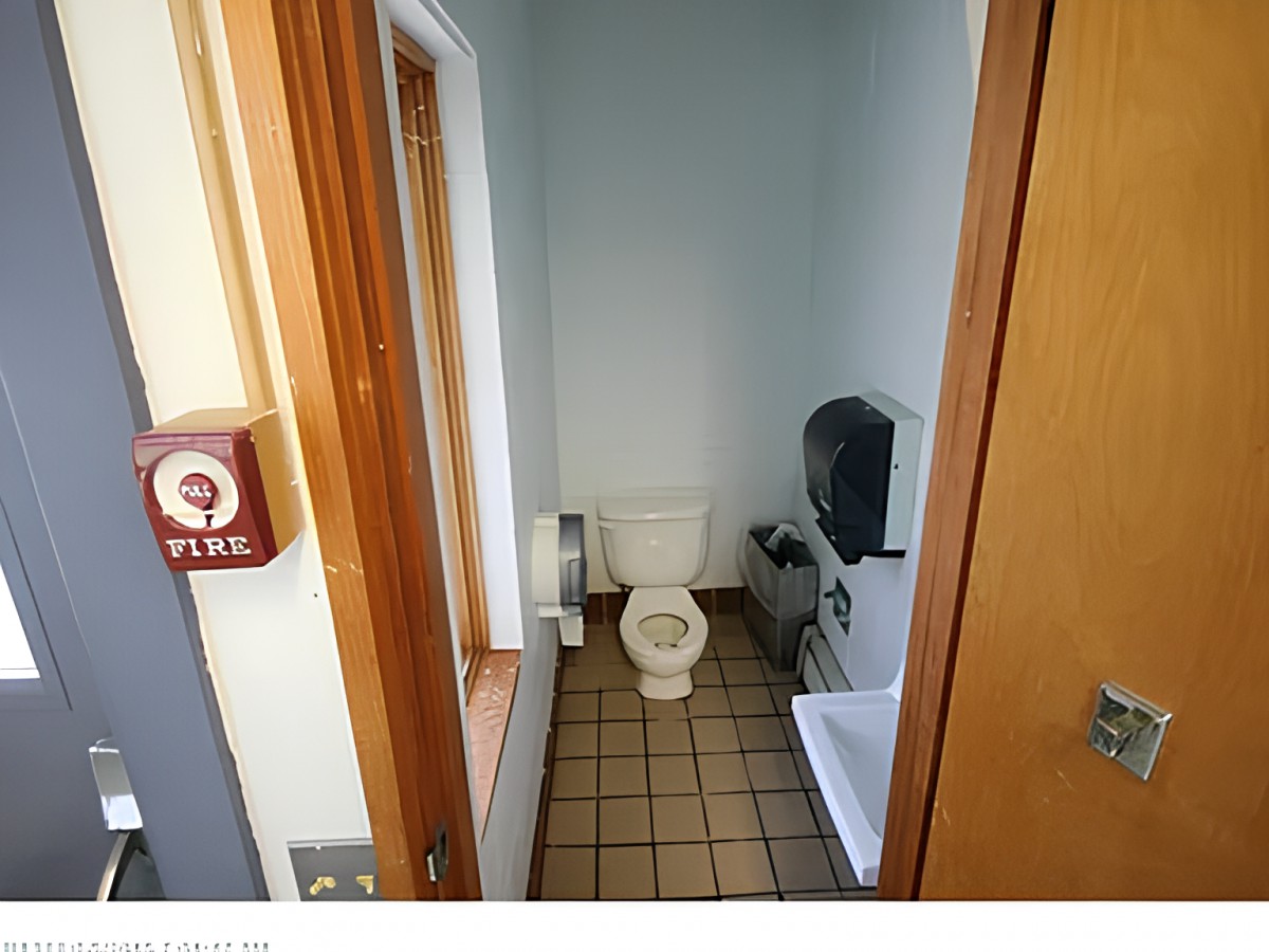A small, tiled bathroom contains a toilet and a sink.