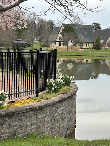 A serene view of a landscaped area featuring a pond, blooming flowers, and a peaceful reflection of a house.