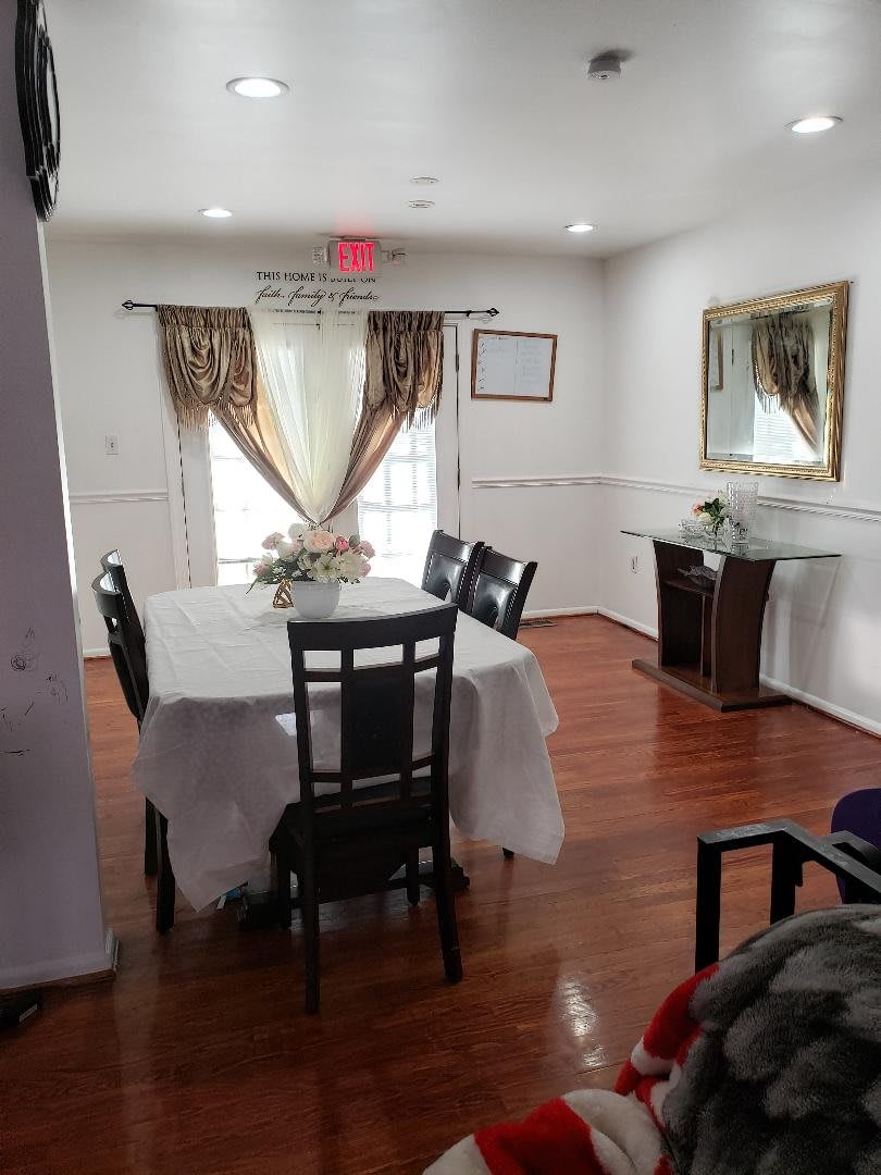 A cozy dining room with a table and chairs, decorated with elegant curtains and a mirror on the wall.