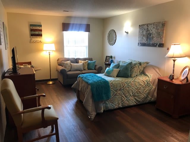 A cozy bedroom with a comfortable bed, sofa, and warm lighting.
