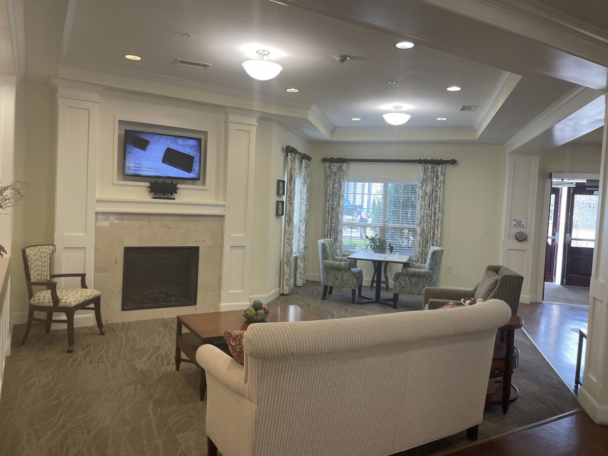 A cozy living room with a fireplace and seating area, featuring a television mounted above the mantle.