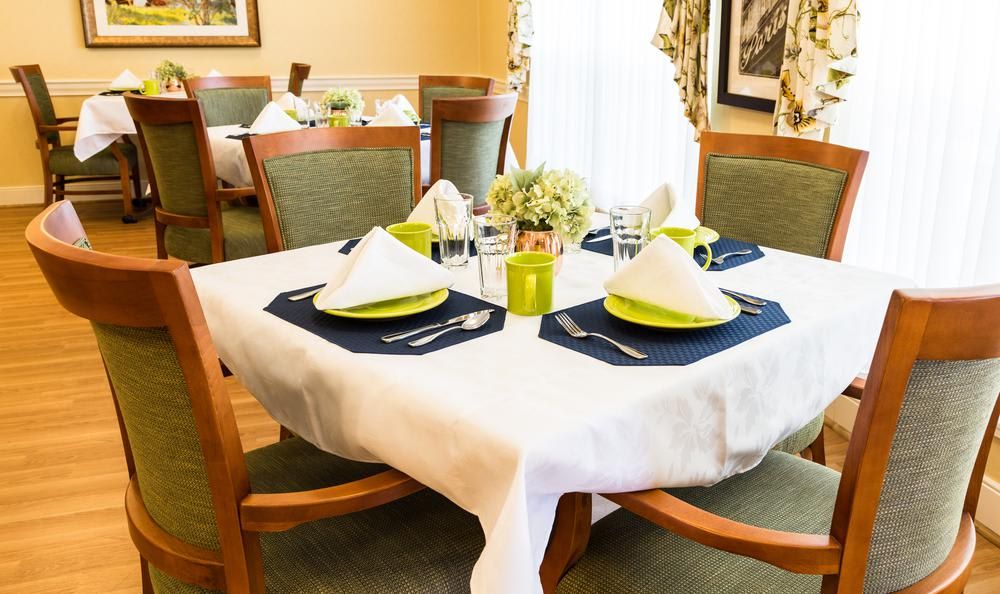 A neatly set dining table with elegant place settings, including folded napkins and a floral centerpiece.