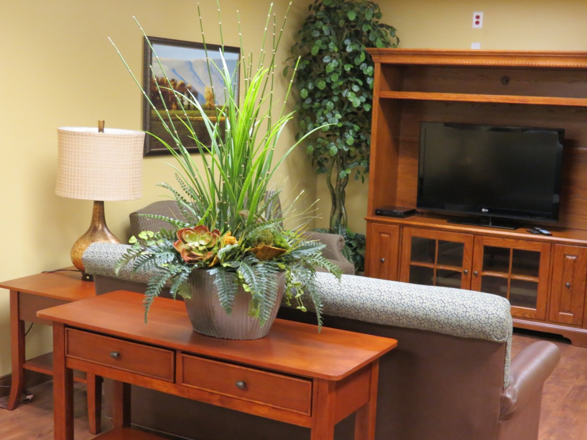 A cozy living room with a wooden table, decorative indoor plant, sofa, and TV stand.