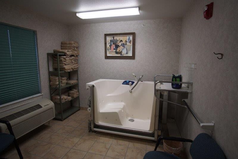 A modern bathroom with a walk-in bathtub and neatly stacked towels.
