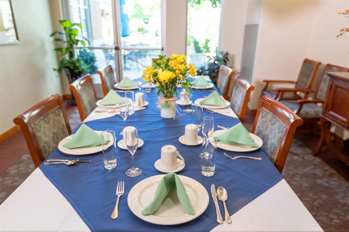 A formal dining table set with elegant tableware and a centerpiece of yellow flowers.
