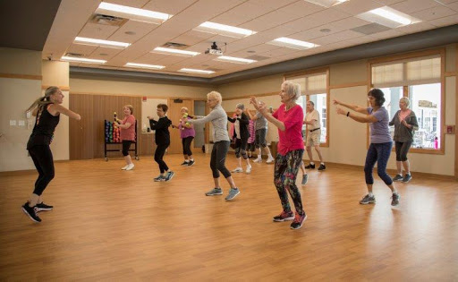 A group of individuals participating in a lively dance workout class indoors.