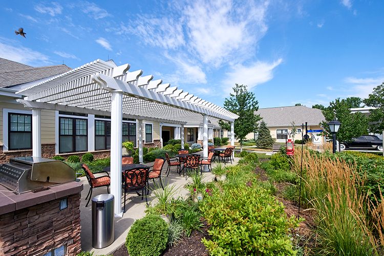 A beautifully landscaped patio area with outdoor seating under a pergola on a sunny day.