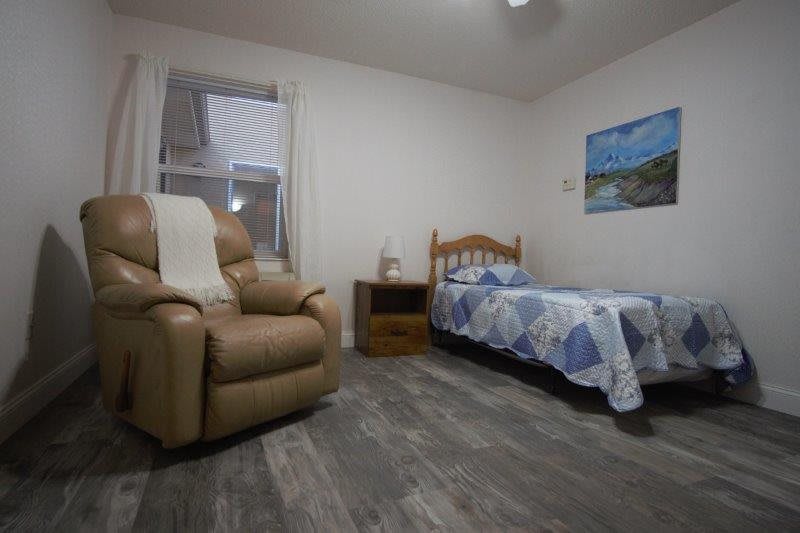 A cozy bedroom with a single bed and a recliner, featuring minimalist decor.